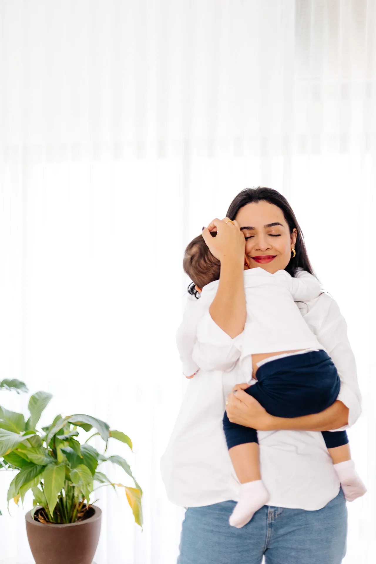 Nanda abraçando seu filho junto à janela